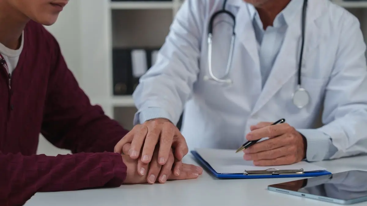 Arzt legt beruhigend die Hand auf die Hand eines Patienten als Symbol fuer empathische Fehlerkommunikation im Arzt Patient Gespraech