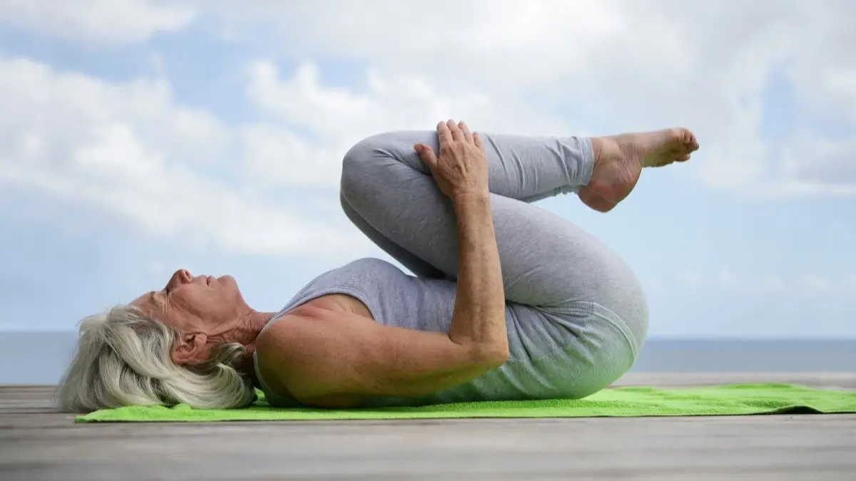 Aeltere Frau in der Menopause macht Gymnastikuebungen auf einer Matte als Symbol fuer Muskelerhalt mit Kreatin Monohydrat