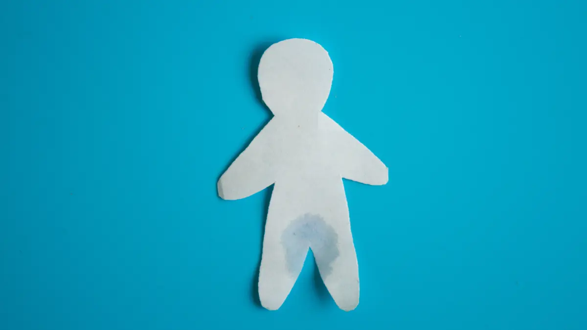 papierfigur eines mannes mit nasser hose als symbolbild fuer maennliche harninkontinenz