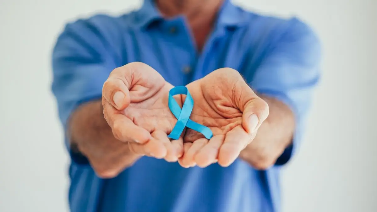Mann haelt eine blaue Schleife in den aufgehaltenen Haenden als Symbol fuer Prostatakrebs Frueherkennung und den negativen IQWIG Vorbericht zur PCa Frueherkennung