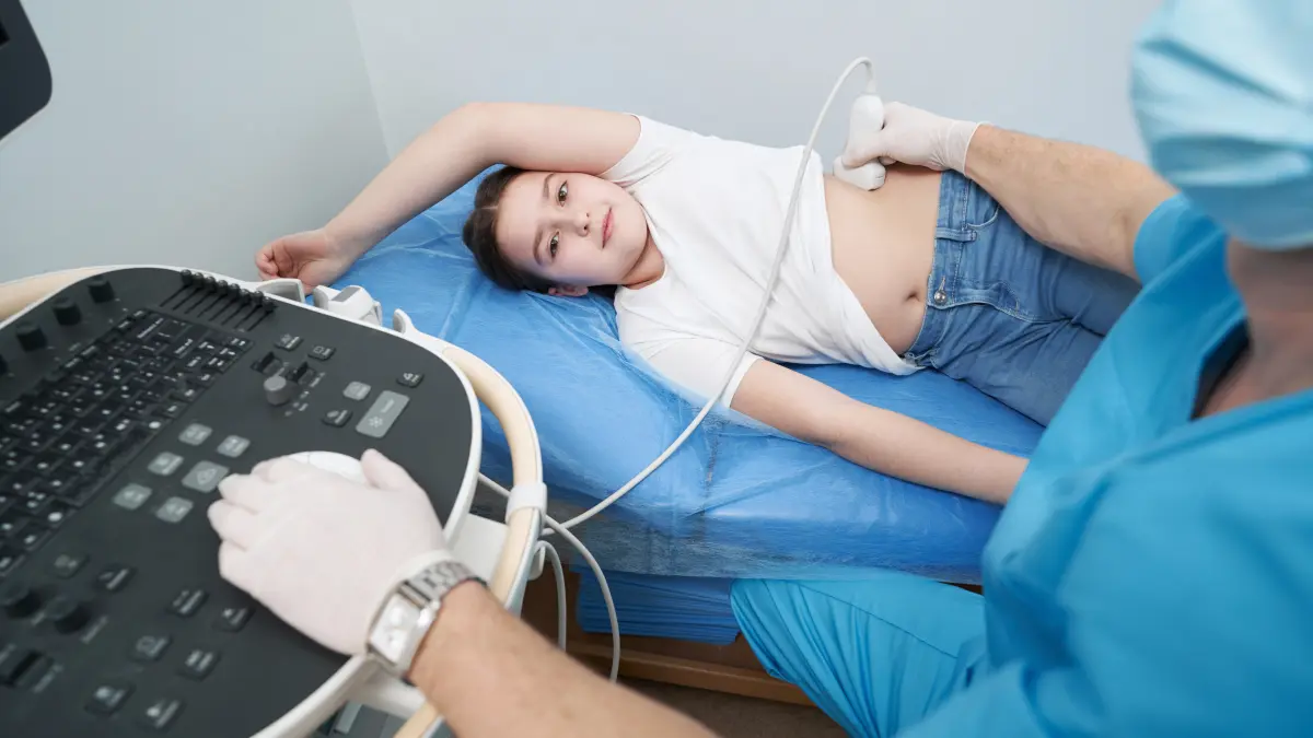 Ultraschalluntersuchung des Abdomens bei einem Mädchen in Seitenlage auf einer Untersuchungsliege