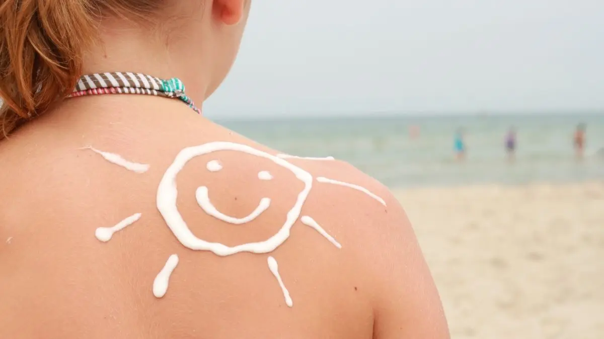Kind mit Sonne aus Sonnencreme auf der Schulter als Symbol fuer natuerlich entspannt durch den Sommer
