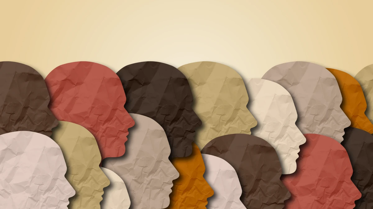Stilisierte Papier-Silhouetten menschlicher Köpfe in verschiedenen Hauttönen – Symbol für Diversität und Rassismus im Gesundheitswesen