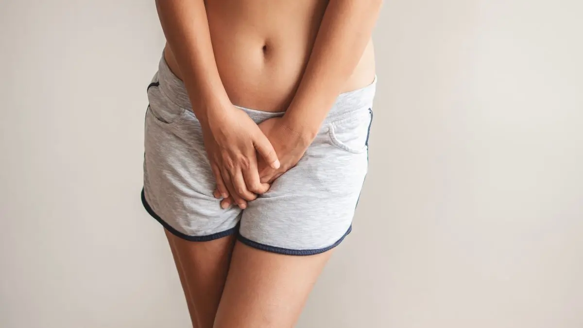 Frau haelt sich diskret den Intimbereich als Symbol fuer vulvovaginale Beschwerden, die richtig behandelt werden muessen